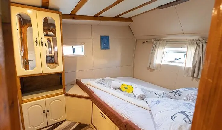 Cozy yacht cabin with bed and wooden paneling on Gardelin, a plush double berth