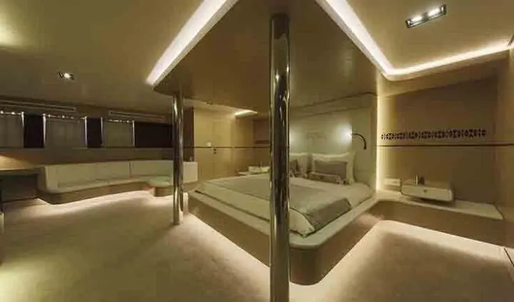 Master cabin with king bed, ensuite, warm lighting, beige decor, metal columns