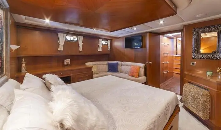 Arabella yacht cabin with large bed, wooden ceiling, and blue cushions