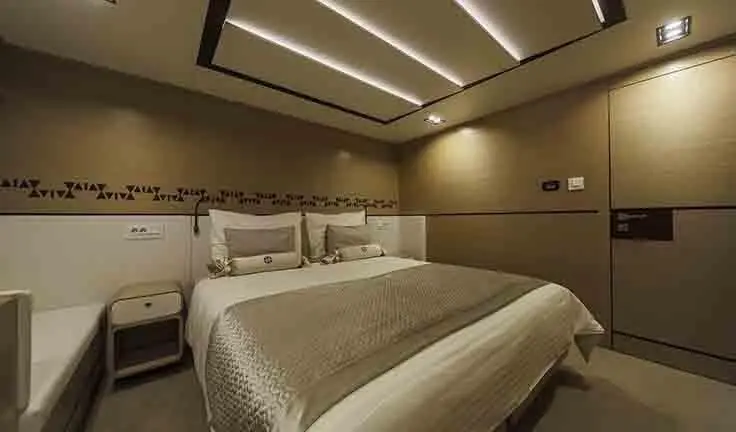 Master cabin with king bed, beige bedding, wood headboard and ensuite door
