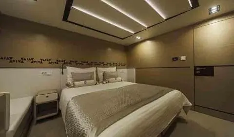 Master cabin with king bed, beige bedding, wood headboard and ensuite door