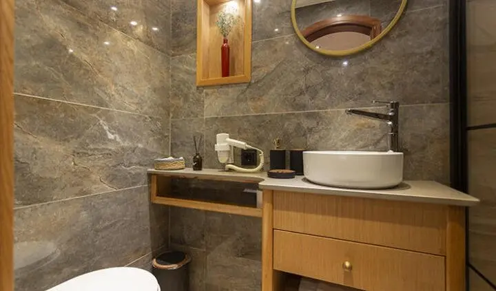 Diva Deniz cabin bathroom with sink, mirror, circular window, and wooden vanity