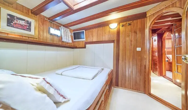 Twin bed cabin interior on a wooden yacht with porthole light and white bedding