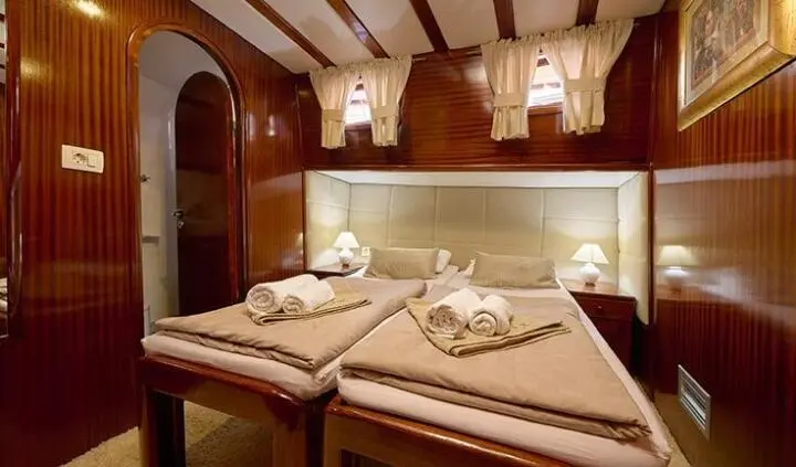 Twin berths in wood-paneled cabin with neatly made beds and pillows