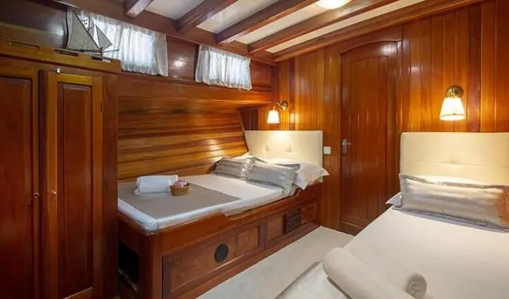 Andi Star cabin with triple bed setup, wood paneling, porthole light