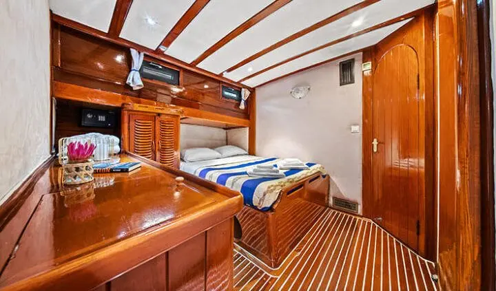Inside Eleganza yacht cabin with twin beds, wooden cabinetry, and striped carpet