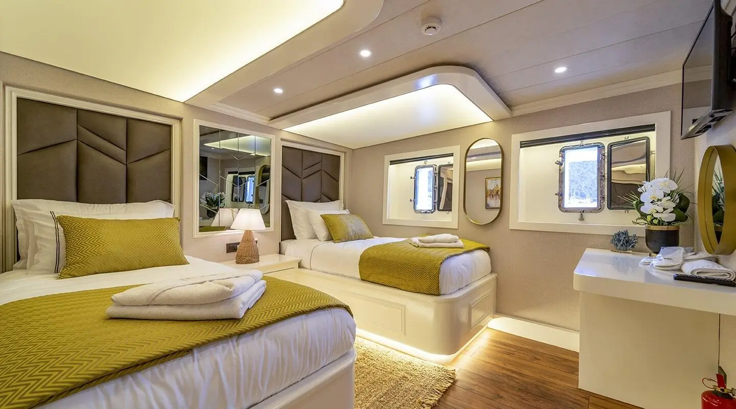 Luxurious yacht interior with sunlit cabins, portholes, and seating area aboard Queen Of Makri