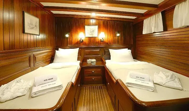 Twin wooden berths in a yacht cabin with polished wood walls and warm lighting