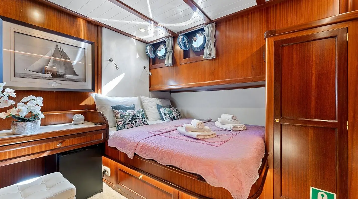 Luxurious yacht cabin with wooden cabinetry, bed, and soft lighting at dusk