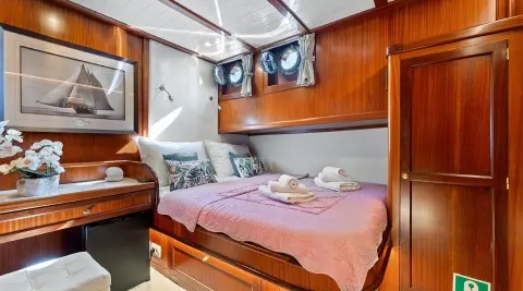 Luxurious yacht cabin with wooden cabinetry, bed, and soft lighting at dusk