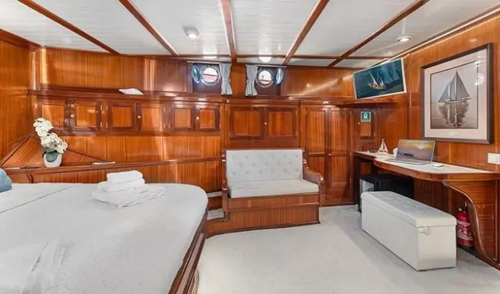 Luxurious yacht cabin with wooden cabinetry, two single beds, and a central seating area