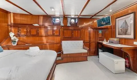 Luxurious yacht cabin with wooden cabinetry, two single beds, and a central seating area