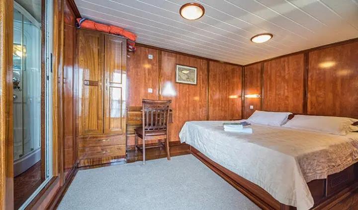 Master cabin on Luna yacht with king bed, wood paneling, and ensuite.