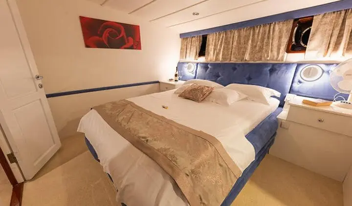 Aurum yacht cabin with two single beds, beige bedding and blue curtains