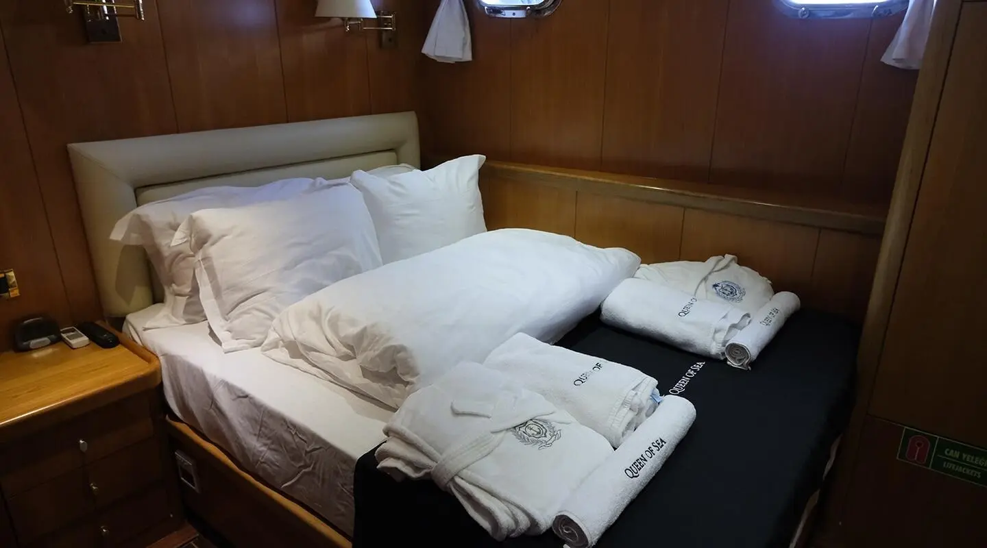 Queen Of Sea yacht interior with neatly made beds and folded towels