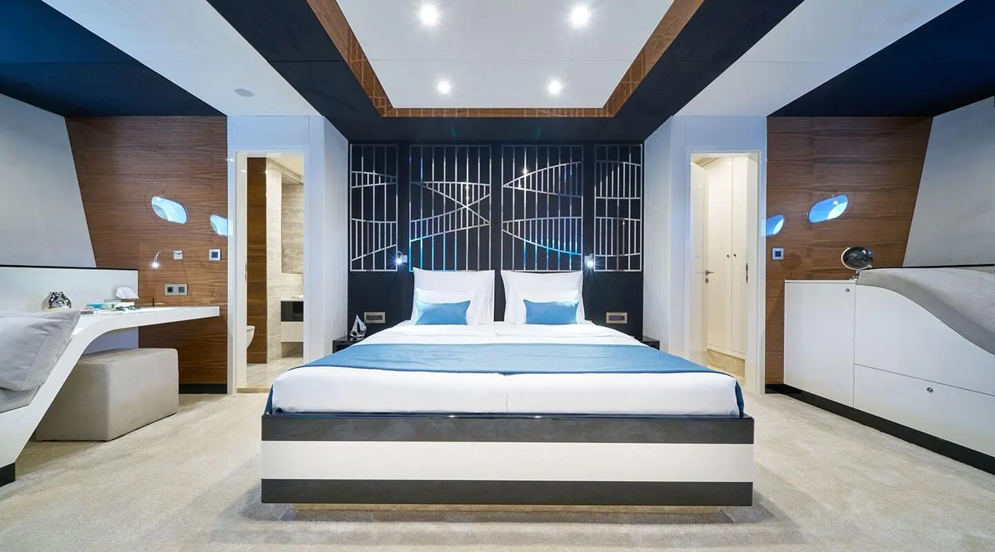 Acapella yacht master cabin with blue-and-white bed, navy walls, and steps leading into room