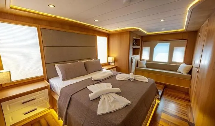 Two neatly made beds in a warm cabin with pillows and wood paneling