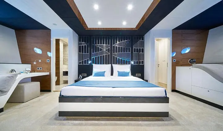 Master cabin with king bed, blue cushions, ensuite doorway, bedside lamps