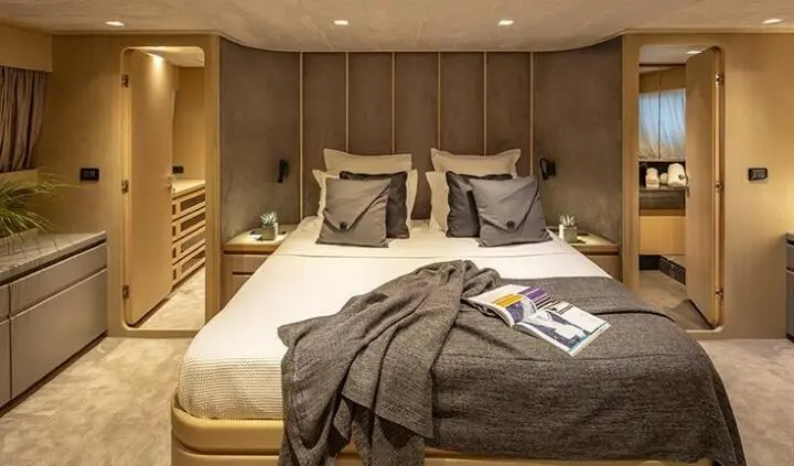 Luxurious yacht cabin with king bed, neutral tones, pillows, and bedside lamps