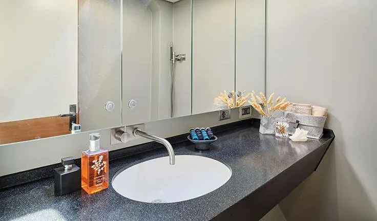 Master cabin with dual sinks, large mirror, and beige countertop on Aizu yacht