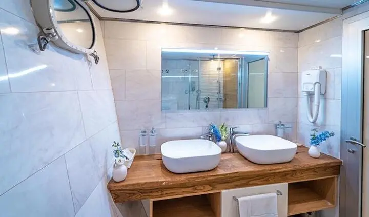 Yacht cabin with twin sinks and large mirror above wooden vanity