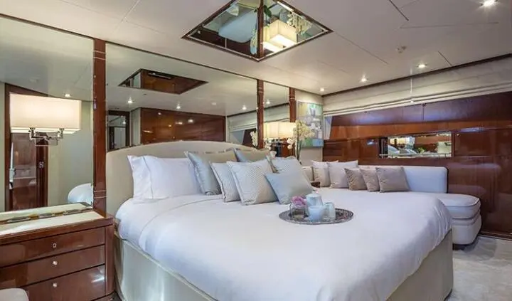 Grace yacht cabin with king bed, white linens, wooden cabinetry, porthole light