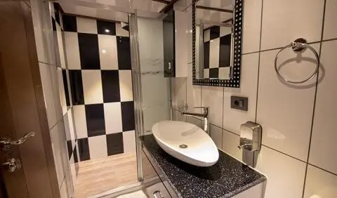 Nevra Queen cabin bedroom with white bed, checkered bathroom tiles visible