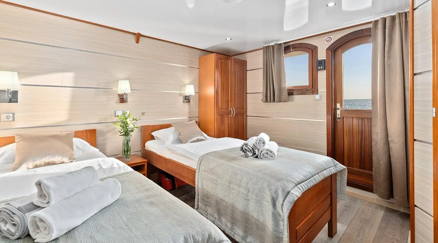 Karizma yacht bedroom with two twin beds, nightstands, and wooden cabinetry