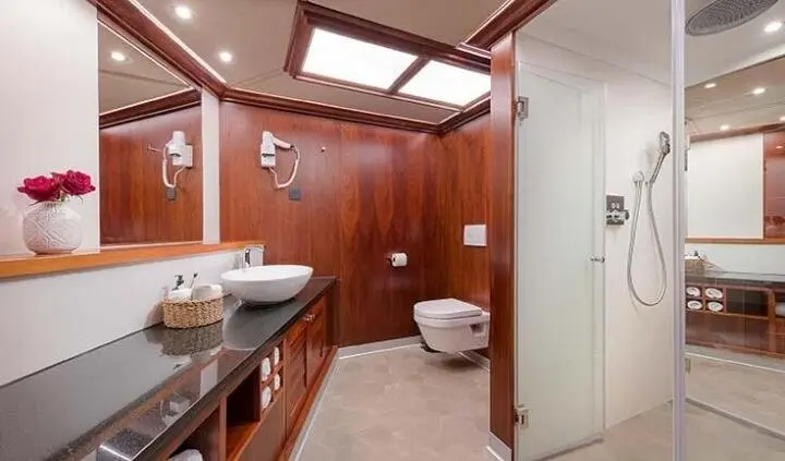 Bathroom on Lady Gita yacht with wooden vanity, mirror, toilet and sink