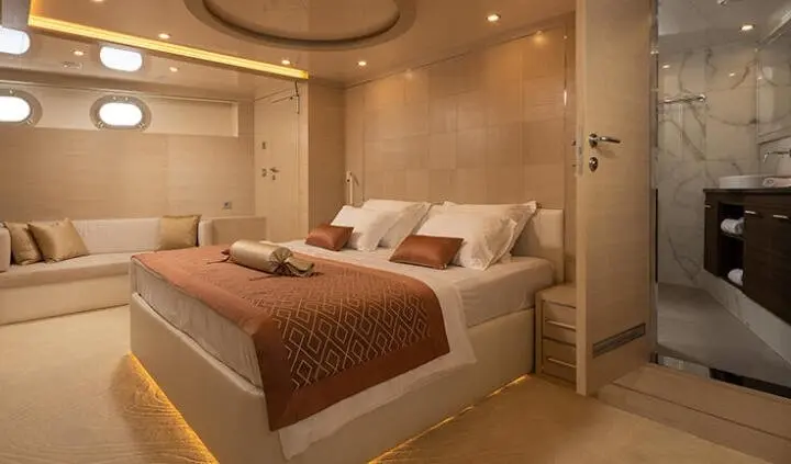 Love Story yacht cabin with large bed, white linens, brown throw, soft lighting