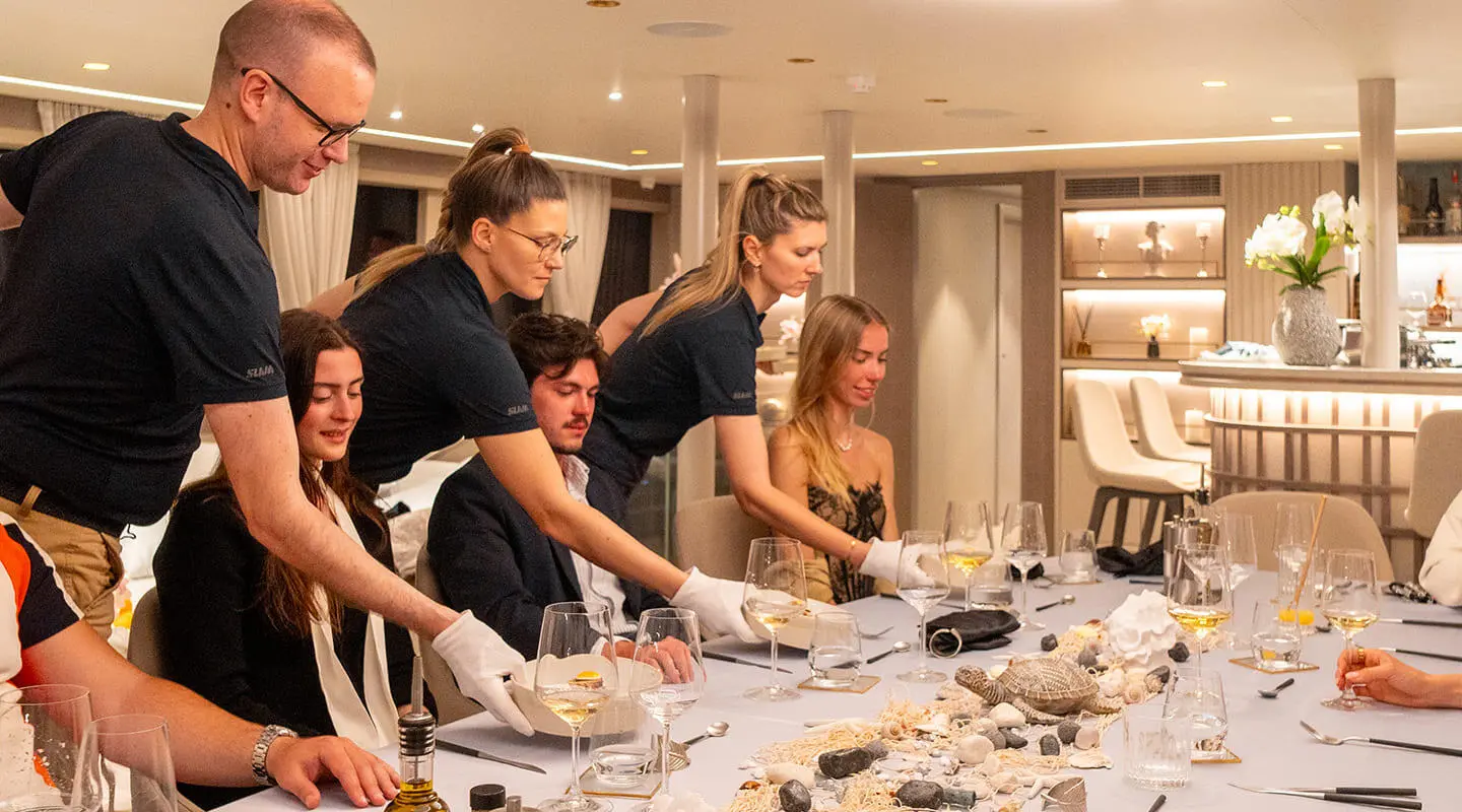 Nocturno yacht guests dining indoors in a well-lit, elegant salon aboard