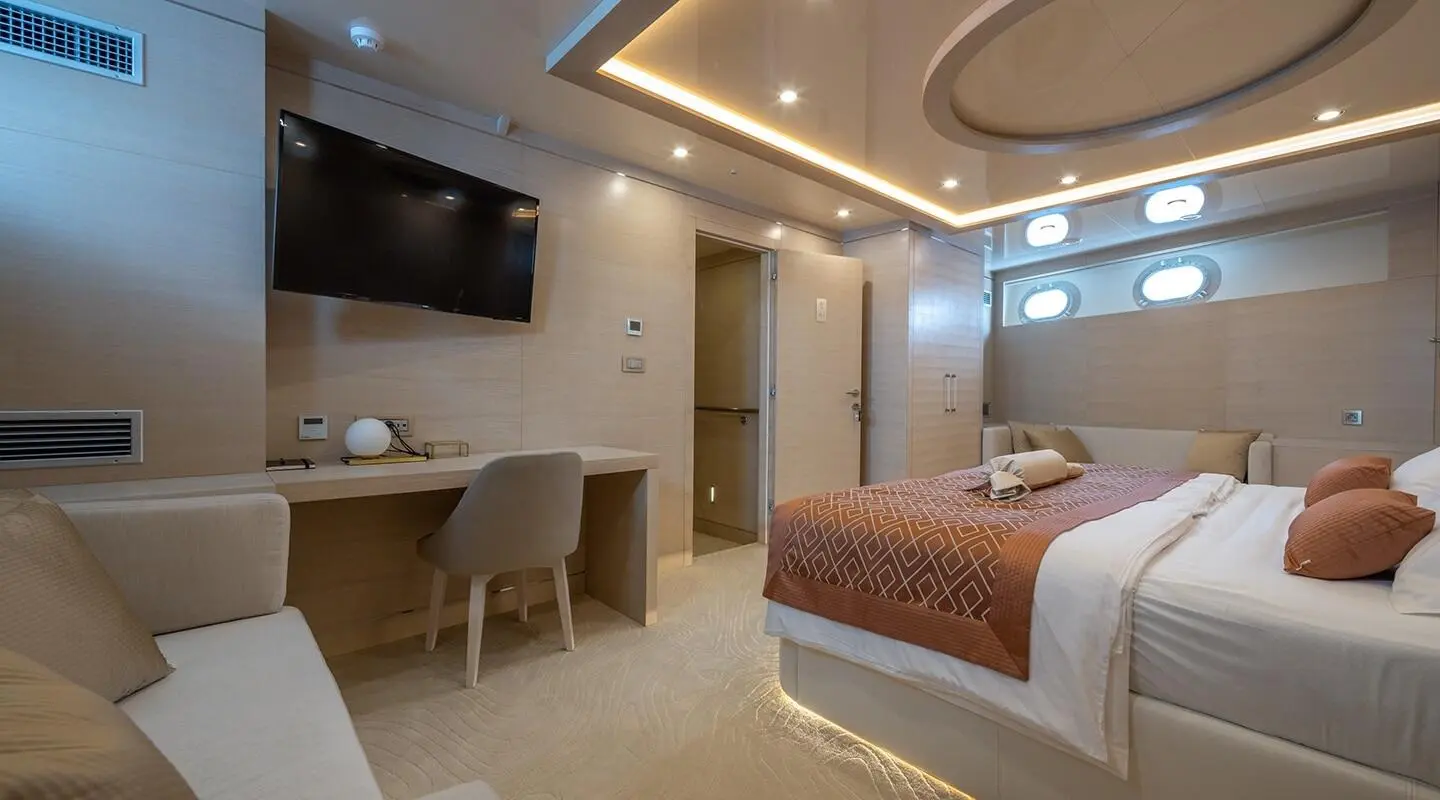Love Story yacht interior with a bed, desk, and seating area at sunset