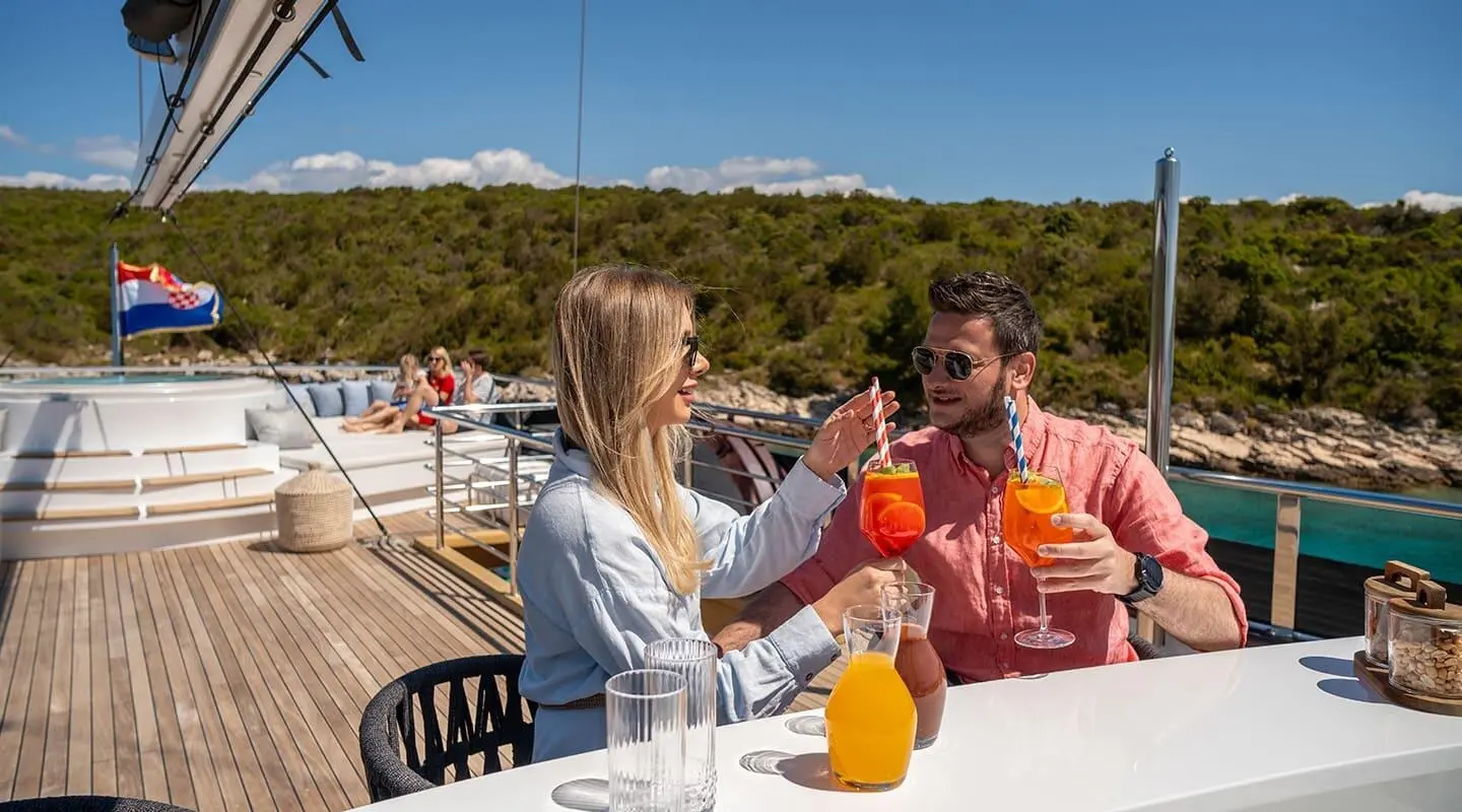 Anima Maris yacht at sunset with two guests dining on deck near water