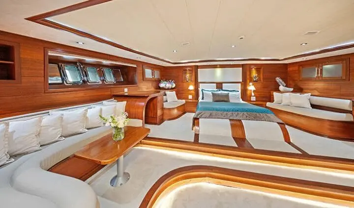 Master cabin with king bed, wood cabinetry, portholes, and seating area