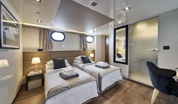 Twin cabin ensuite aboard Rara Avis yacht with two single beds and porthole