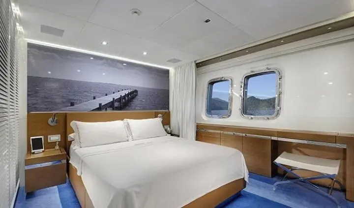 Morning Star yacht master cabin with king bed, ensuite, blue carpeting, porthole windows