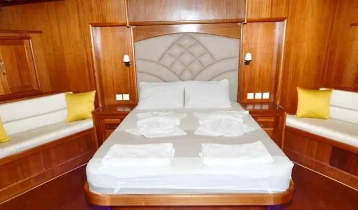 Prenses Esila cabin interior with plush upholstered headboard and white linens