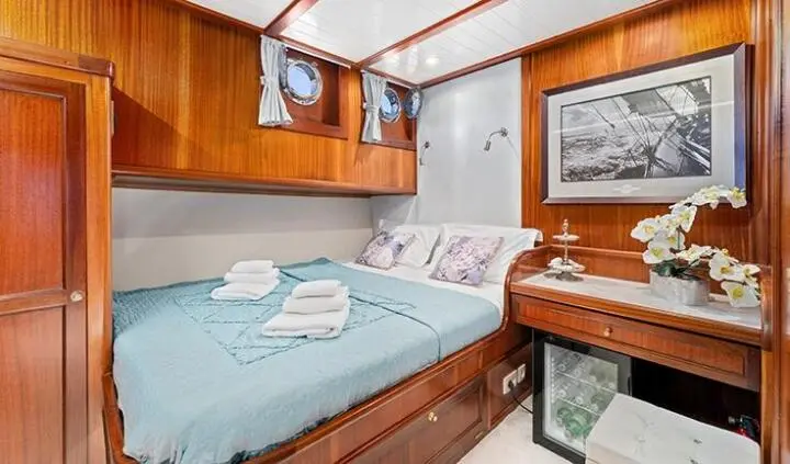 Master cabin with a king bed, teal bedding, wood cabinetry, and ensuite setup