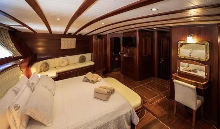 Master cabin with king bed, bedside tables, and warm wood paneling on Arif Kaptan A