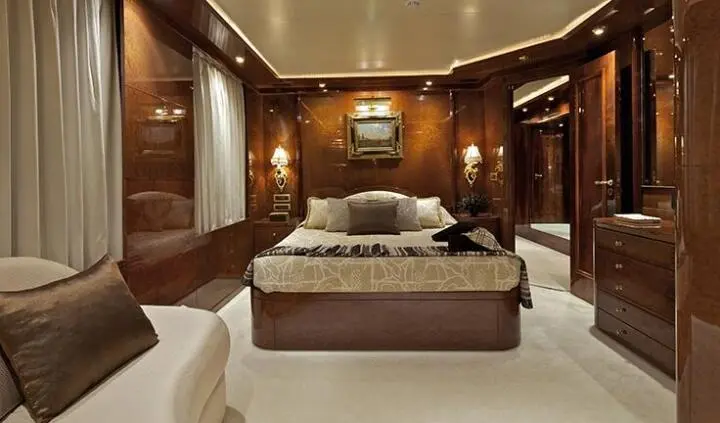 Master cabin with king bed, wood paneled walls, and ensuite doorway on yacht