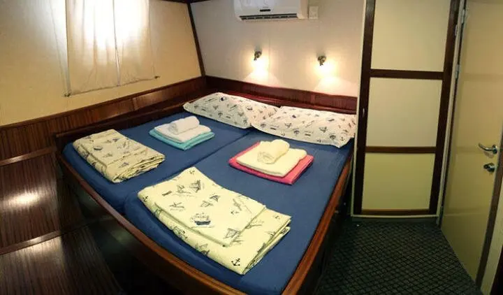 Yacht Tajna Mora cabin with two bunk beds and folded towels on cushions