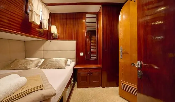 Cozy cabin interior on Linda yacht with wooden cabinets and two beds
