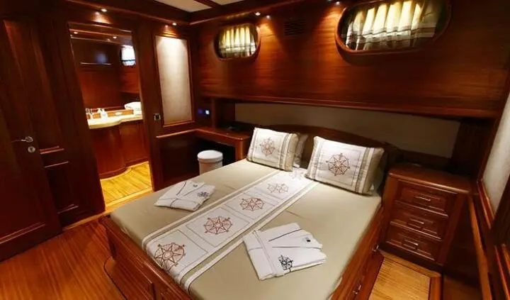 Master cabin with bed on Kaya Guneri 5 yacht, wood paneling and pillows