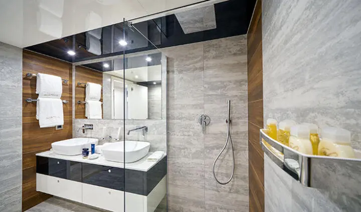 Master cabin with king bed, ensuite, wooden panels, vanity mirror, and glass door