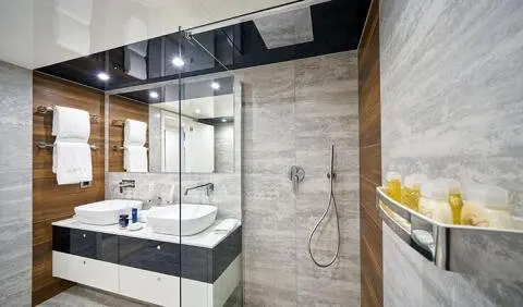 Master cabin with king bed, ensuite, wooden panels, vanity mirror, and glass door