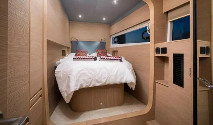 Master cabin with king bed, white bedding, wood panels, and built-in storage