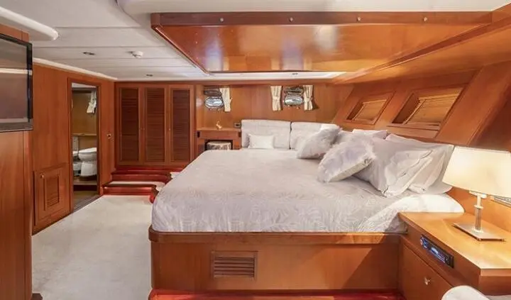 Arabella yacht cabin with king bed, beige bedding, wood paneling, ensuite doorway