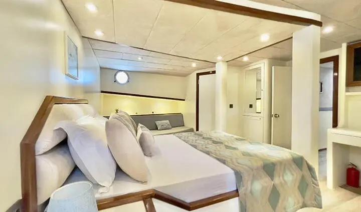 Master cabin with king bed, white bedding, and ensuite bathroom area visible