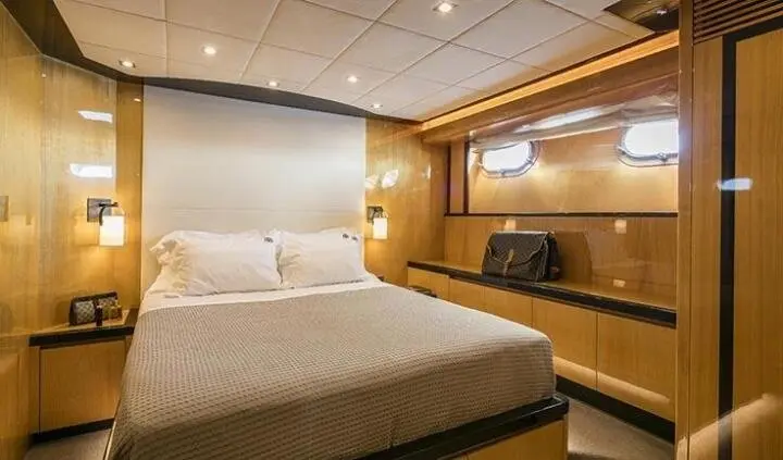 Luxurious yacht cabin with a plush bed, warm wood paneling, and built-in storage