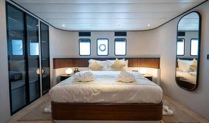 Master cabin with king bed, beige bedding, wood headboard, ensuite door
